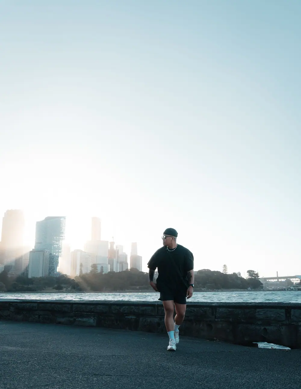 Coureur à contre-jour sur une route, la ville dans la brume